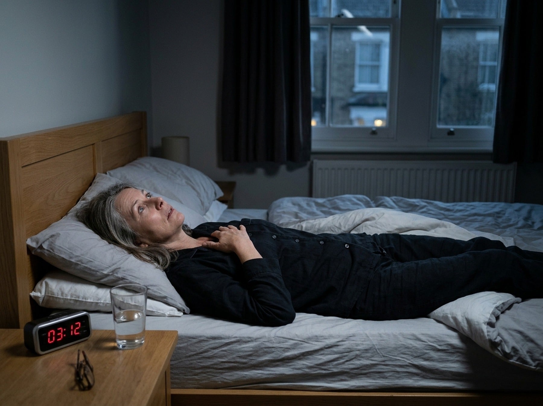 Woman lying awake at 3am with her hand on her chest