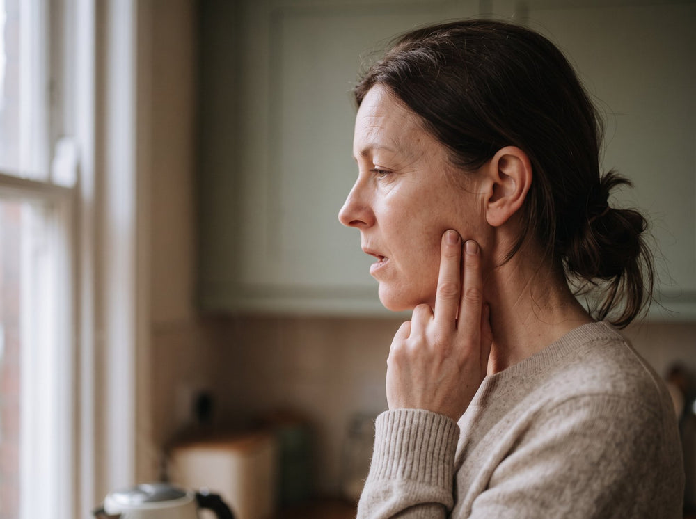 Two fingers pressed on the jaw muscle in front of the ear