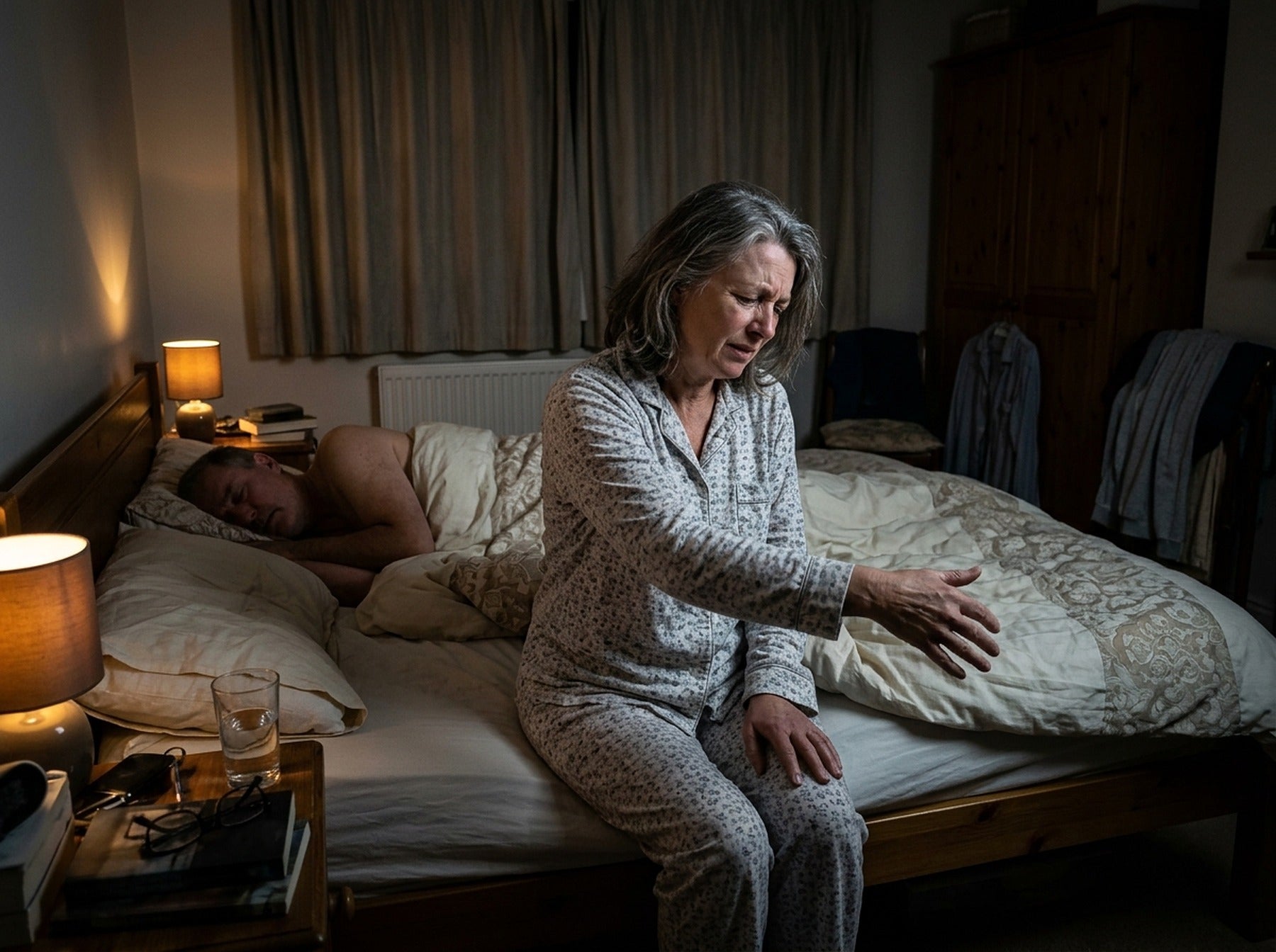 Woman sitting on the edge of her bed at 3am shaking out her arm