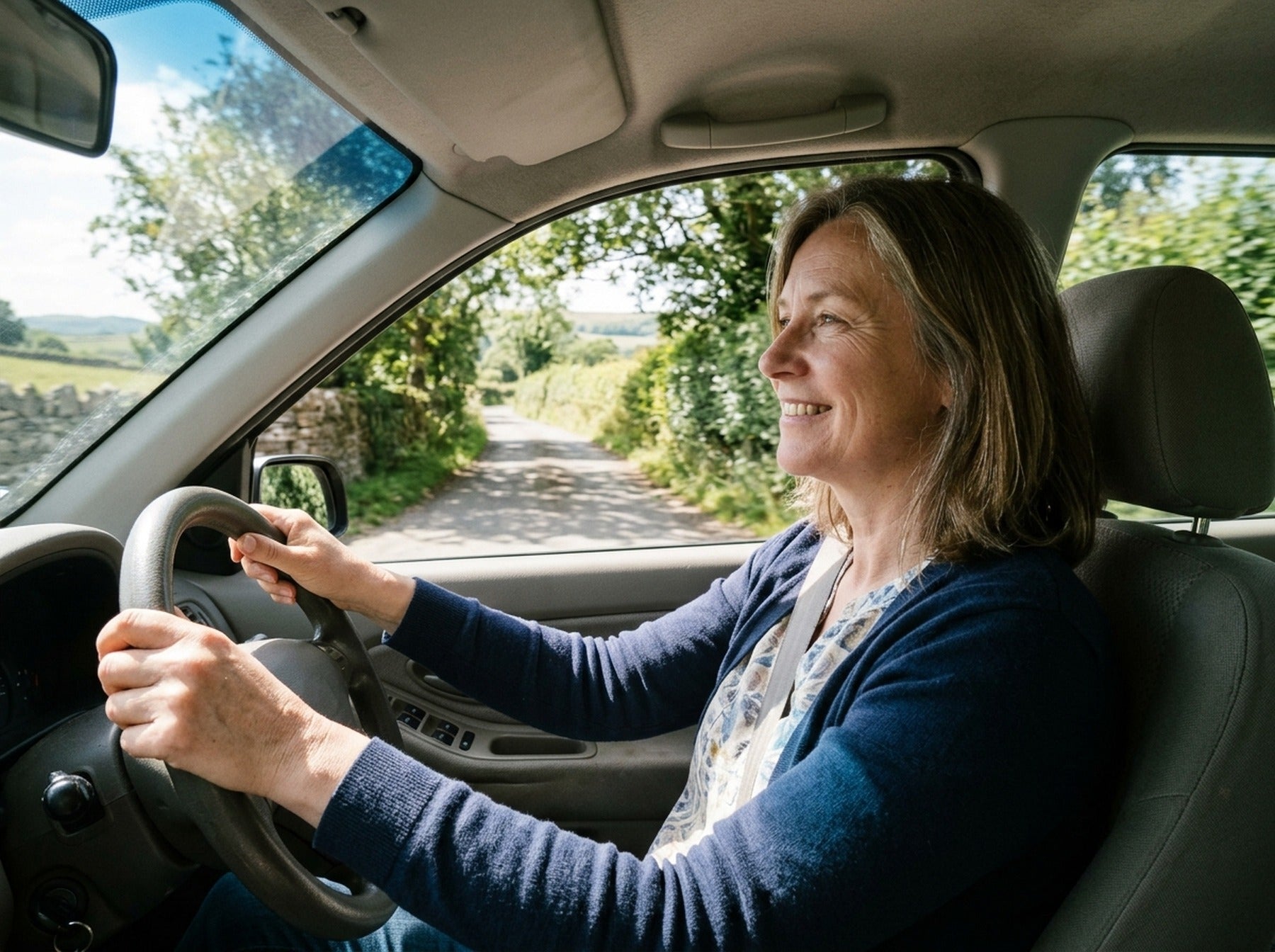 Woman driving on a sunny British country road